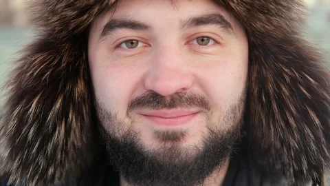 Close-up portrait of a beardy man dressed with fur hat, he is looking at the Stock Footage 265972900