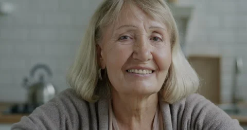 Close-up portrait of beautiful elderly lady with blond hair smiling looking at Stock Footage 241525521