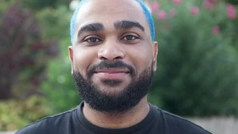 Close-up portrait of black guy with colored hair looking at camera 스톡 동영상 285659249