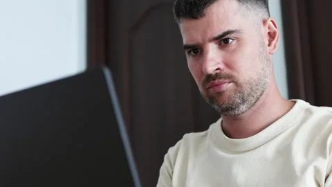 Close up portrait of black haired man looking seriously in screen of laptop. Video stock 310218110
