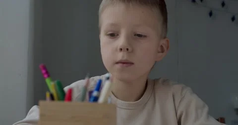 Close up portrait of blonde boy drawing at home sitting at table by window Stock Footage 146937863