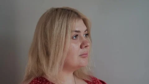 Close-up portrait of blonde thoughtful plus-size woman looking away Stock Footage 268746841