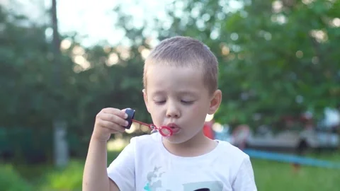 Close-up portrait of a boy blowing soap bubbles Stock Footage 277851641