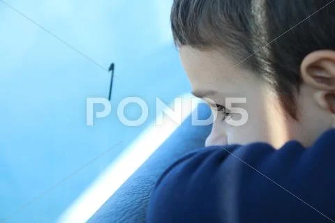 Close-up portrait of a boy looking out of a window on a train journey Stock Photos