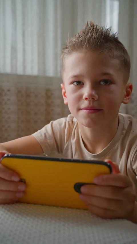 Close-up Portrait of Boy Using Phone, Screen Reflected in Eyes. Video stock 320358204