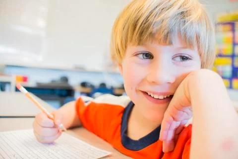 Close up portrait of boy writing in exercise book in classroom Stock Photos