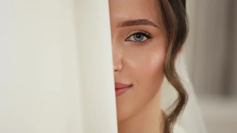 Close-up portrait of bride peeking from behind her wedding dress with one eye Stock Footage 291262323