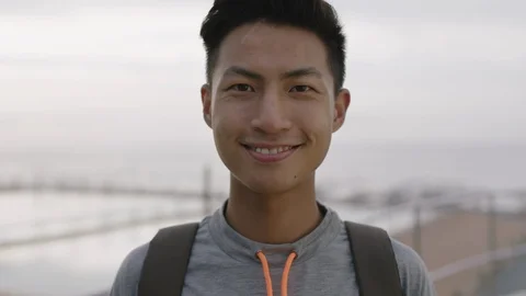 Close up portrait of charming young asian man smiling cheerful optimistic by Stock Footage