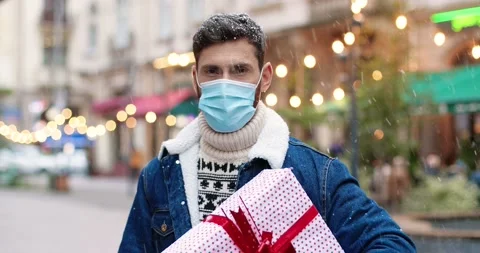 Close up portrait of cheerful handsome guy in medical mask holding christmas Stock Footage 142238895