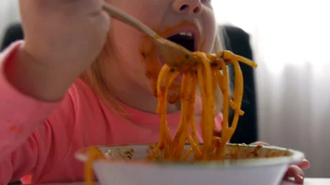 Close up portrait of a child girl eats spaghetti with Stock Footage 135312980