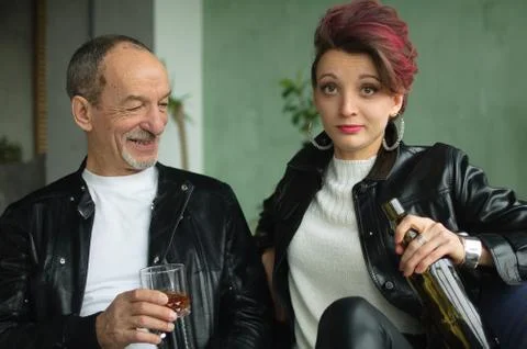Close-up portrait of a couple with age difference drinking an alcohol in loft Stock Photos