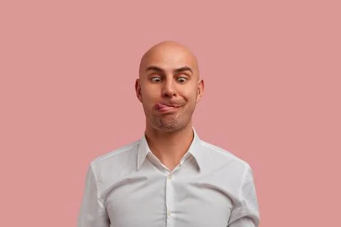Close-up portrait of crazy bald guy with bristle makes funny face, looking do Stock Photos