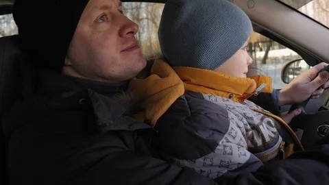 Close-up portrait of a curious boy driving a car with his father in winter. Stock Footage 126932218