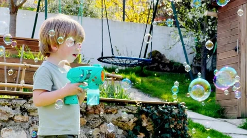 Close portrait of a cute boy play with soap bubble gun Stock Footage 204875255