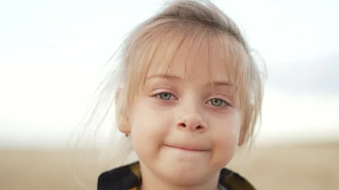 Close-up portrait of cute fair-haired girl. child looks into camera lens. One Vídeo Stock 252108938