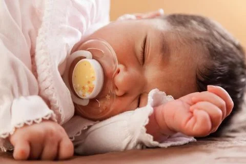 Close up portrait of a cute two weeks old newborn baby girl wearing soft pink Stock Photos