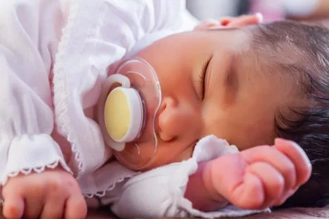 Close up portrait of a cute two weeks old newborn baby girl wearing soft pink Stock Photos