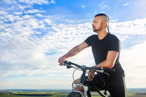 Close-up portrait of the cyclist against beautiful blue sky with clouds. Stock Photos