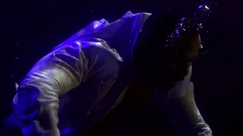 Close-up portrait of a dark-skinned man in a white shirt who is under water. It 库存影片 134739268