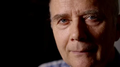 Close-up portrait of an elderly man in a dark room Stockbeeldmateriaal 87745705