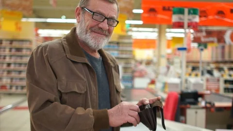 Close portrait of an elderly man with a purse in his hands in the supermarket Stock Footage 101355556