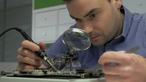 Close-up Portrait of Electronics Maintenance Engineer Soldering Motherboard Stock Footage 133000079