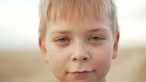 Close-up portrait of a fair-haired boy. The child looks into the camera lens Vídeos de archivo 252108920