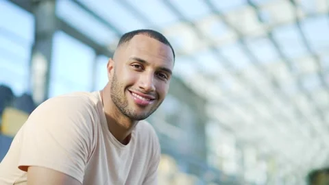 Close up portrait of a fit young man in a t-shirt sitting in an urban city  Stock Footage 234878139