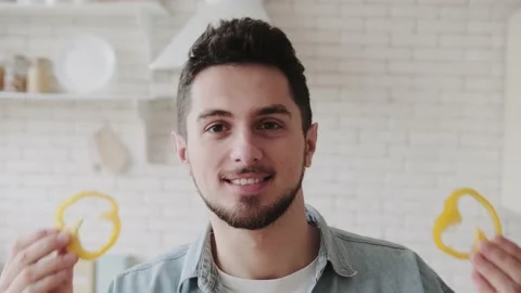 Close-up portrait of a funny young man with slices of pepper in his hands near Video stock 236492208