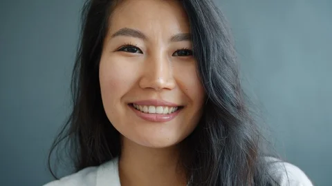 Close-up portrait of good-looking Asian lady smiling on gray background Stock Footage