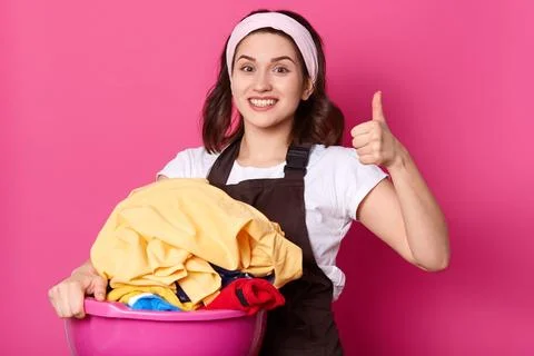 Close up portrait of good looking slender housewife holding pink basin with.. Stock Photos