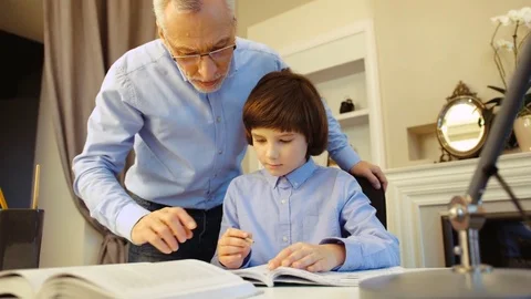 Close up portrait of grandfather watching how his cute grandson making homework Stock Footage