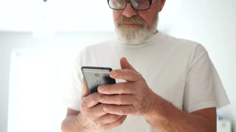 Close portrait of a gray-bearded man in glasses and a white T-shirt is using a Stock Footage 120800042