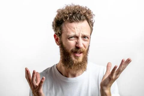 Close up portrait of grumpy young bearded man in t-shirt looking at camera. Stock Photos