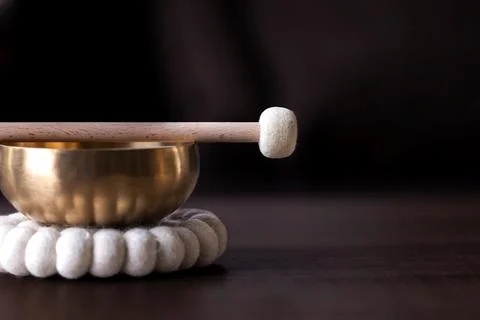 A close up portrait of half of a tibetan singing bowl with a mallet on it a.. Stock Photos