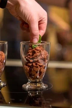 A close up portrait of a hand putting a leaf of mint on top of some sweet and Stock Photos