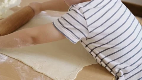 Close-up portrait of the hands of a boy rolling out dough with a rolling pin in Stock Footage 176590514