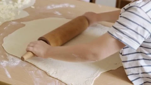 Close-up portrait of the hands of a boy rolling out dough on a table with a Stock Footage 196126866