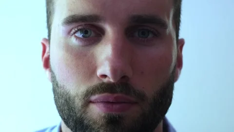 Close up portrait of a handsome man with a beard opening his beautiful blue Vídeos de archivo 345115476