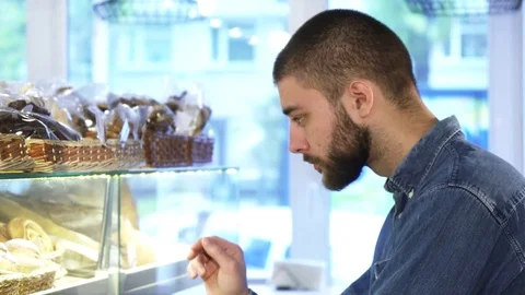 Close up portrait of a handsome man choosing desserts from the showcase Stock Footage 84760503