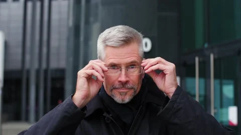 Close-up portrait of handsome middle aged old man putting glasses on his face. Stock Footage 165209266