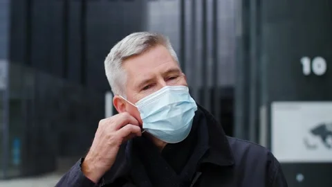 Close-up portrait of handsome middle aged man taking off face mask in city. Stock Footage 165209464