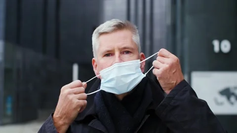 Close-up portrait of handsome middle aged man taking off face mask in city. Stock Footage 165209719