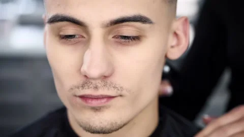Close up portrait of a handsome young man in a barber shop. Hairdresser makes a Stock Footage 236192477