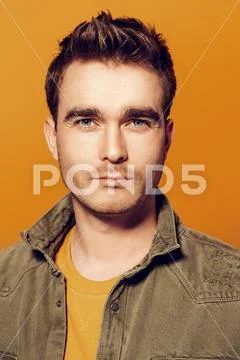 A close up portrait of a handsome young man posing in the studio over the yel Stock Photos
