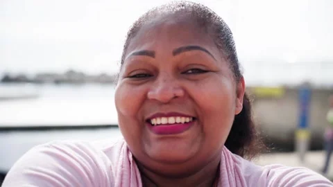 Close up portrait of a happy african plus size woman smiling outdoors by the sea Stock Footage 316764663