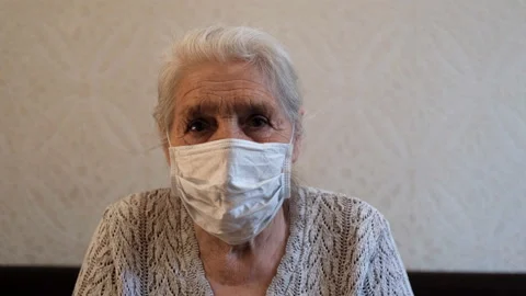Close-up portrait of a happy elderly gray-haired woman in a protective medical Video stock 129566758