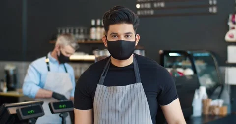 Close up portrait of happy handsome young male waiter in black mask, apron and Stock Footage 159795148
