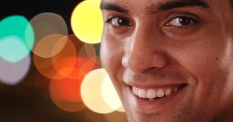 Close up portrait of Happy Latino man looking at camera on city street at night Stock Photos