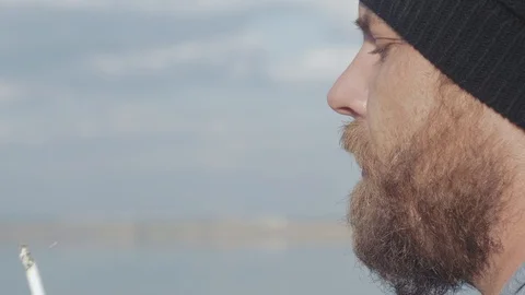 Close-up portrait of a hipster man with a beard smoking a cigarette. man smokes Stock Footage 119336697